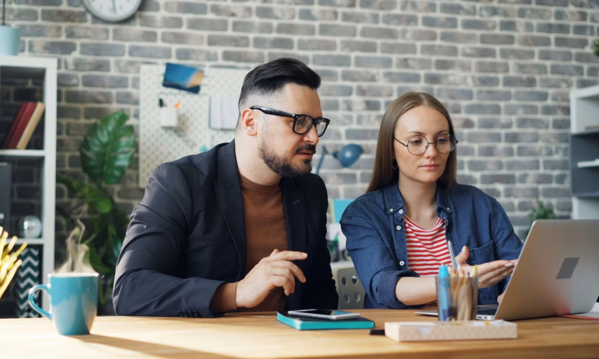 a real estate agent and broker sit in front of a laptop reviewing the ideal email marketing journey to convert leads