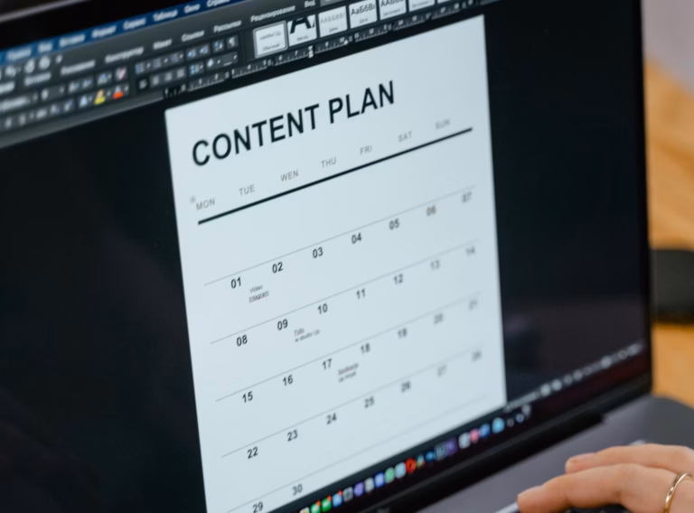 A real estate agent types of a laptop using email marketing tools such as a content calendar to promote her business