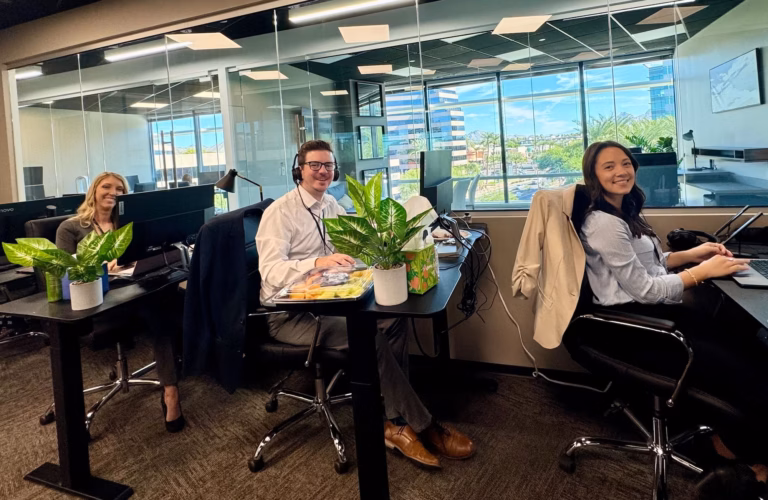 Three staff members in front of desktop computers with headsets on demonstrate the dedication behind the hundreds of Luxury Presence reviews on Google and other platforms