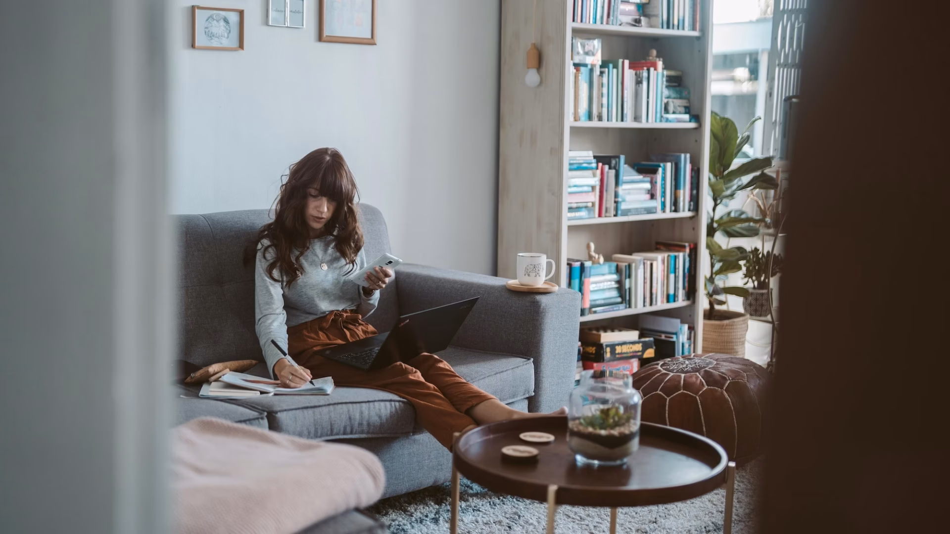 Agent sitting on a couch with a laptop and notebook, working on personalizing her real estate drip campaign templates