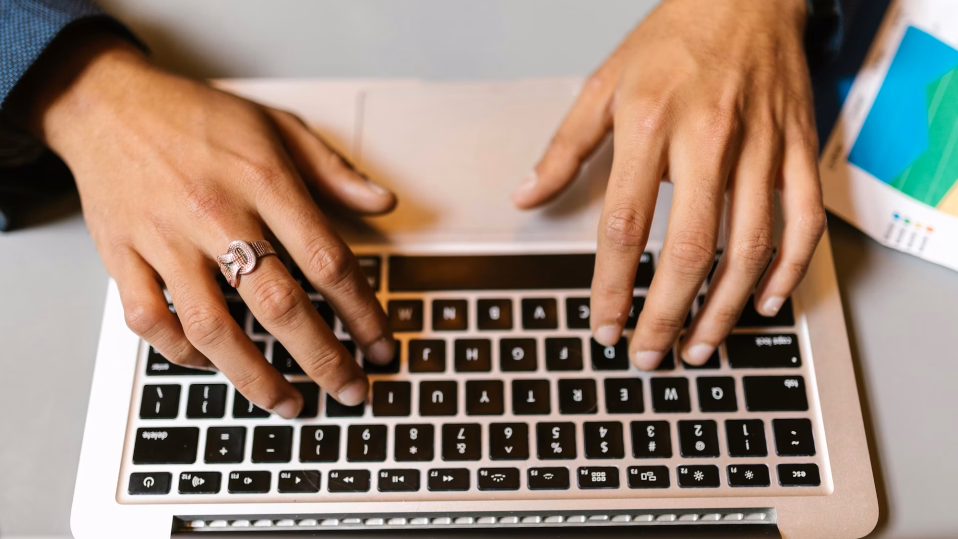 A real estate agent types on their laptop next to a printout of their email marketing strategy template