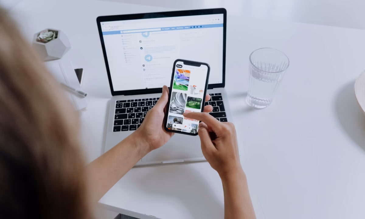 A real estate agent looks at images on her phone in front of her laptop, in an effort at maintaining brand consistency across platforms