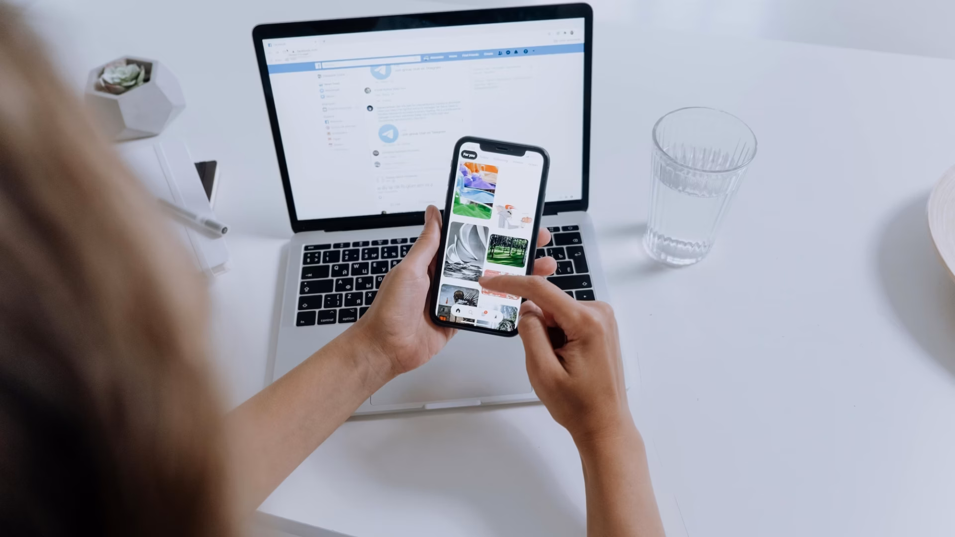 A real estate agent looks at images on her phone in front of her laptop, in an effort at maintaining brand consistency across platforms