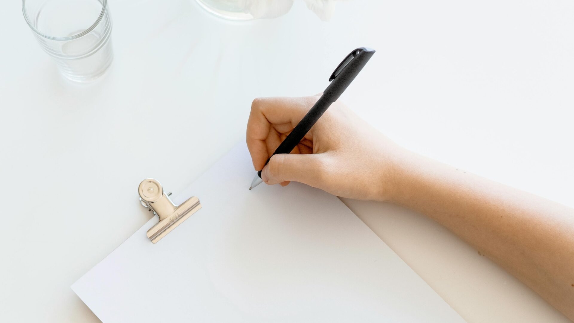 Real estate agent writing with a black pen on a white pad of paper, working on creating their personal brand statement