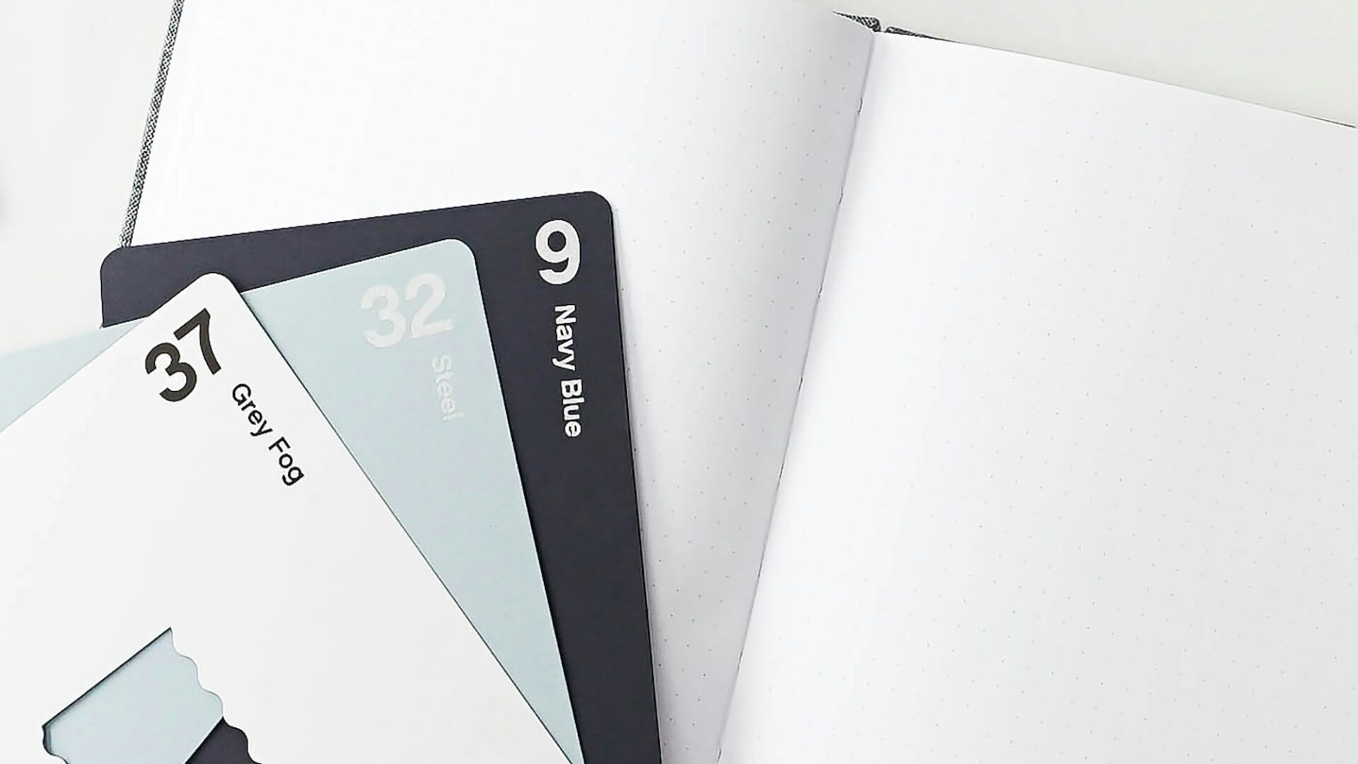 Three color swatches are fanned out on top of a blank journal, representing a brainstorming session to come up with real estate branding ideas