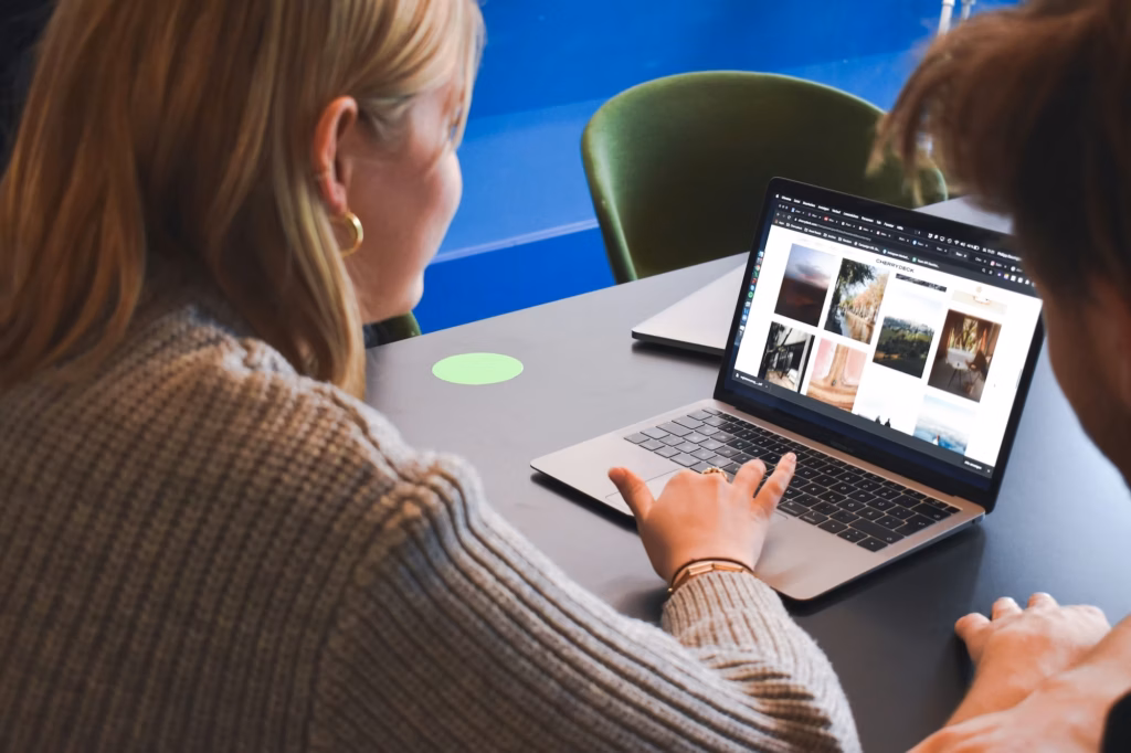 Two agents look at a laptop screen featuring many real estate email templates to choose from