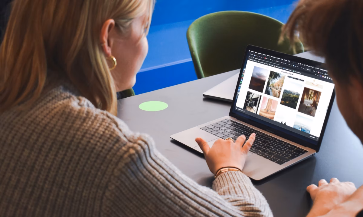 Two agents look at a laptop screen featuring many real estate email templates to choose from