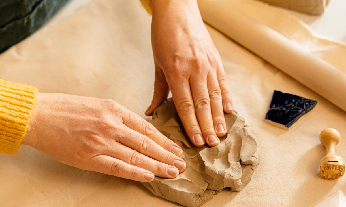 Two hands shape clay on a table, representing the process of determining your brand personality