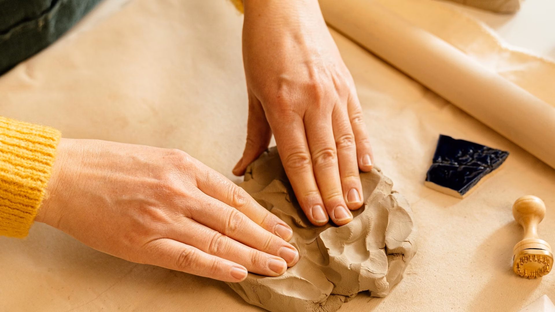 Two hands shape clay on a table, representing the process of determining your brand personality