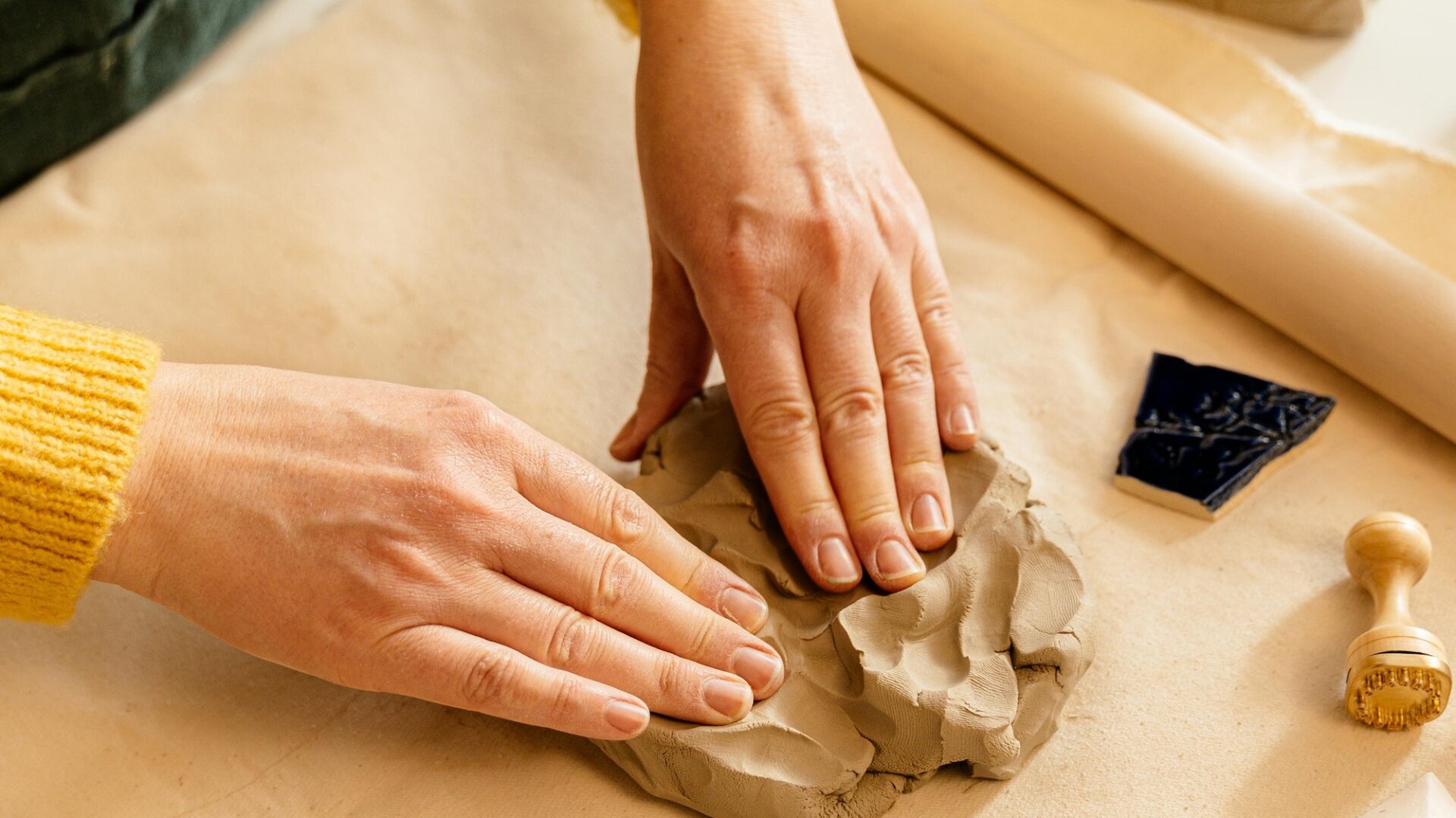 Two hands shape clay on a table, representing the process of determining your brand personality