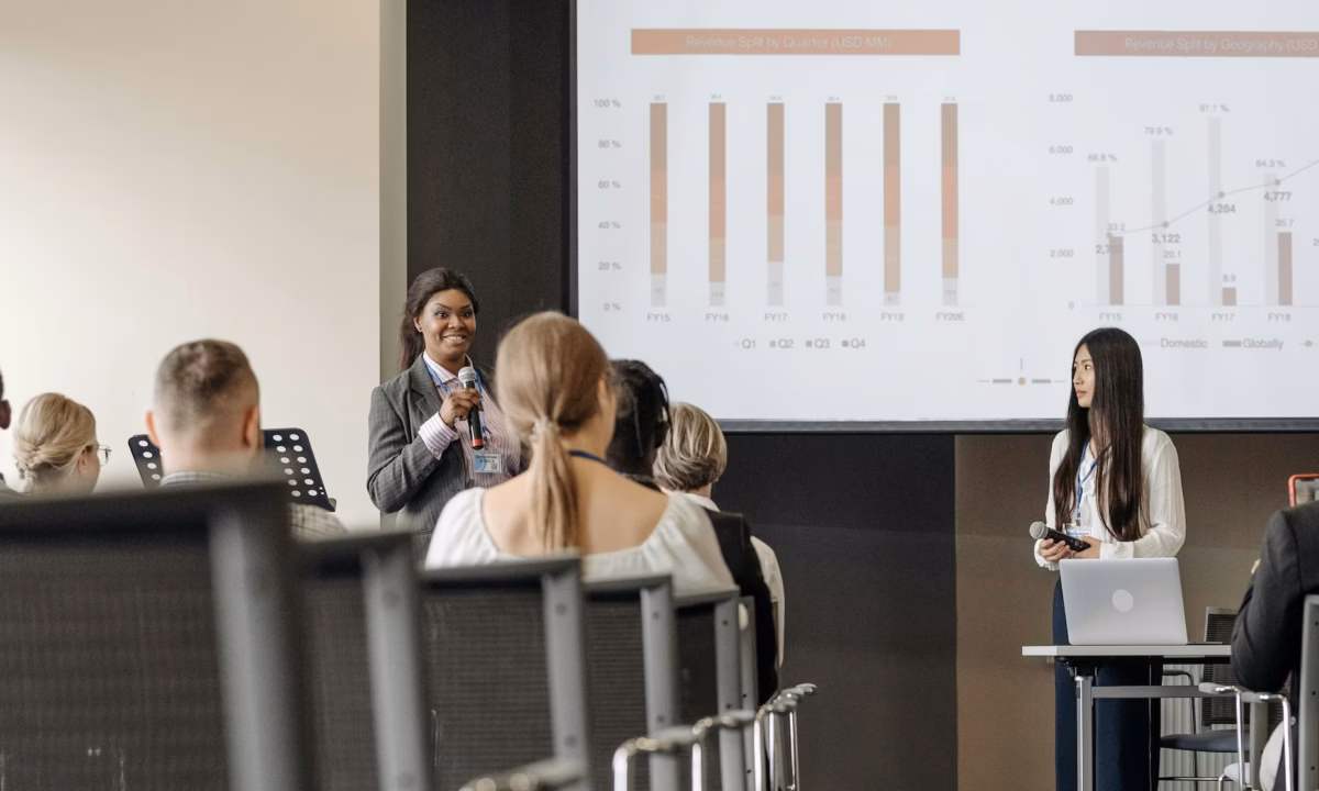 A real estate broker stands in front of a group of agents demonstrating her thought leadership skills