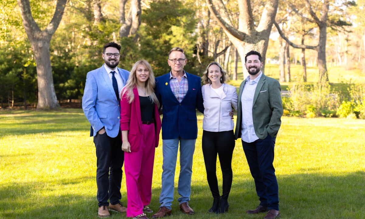 The guthrie schofield real estate team poses together on a green lawn in front of trees