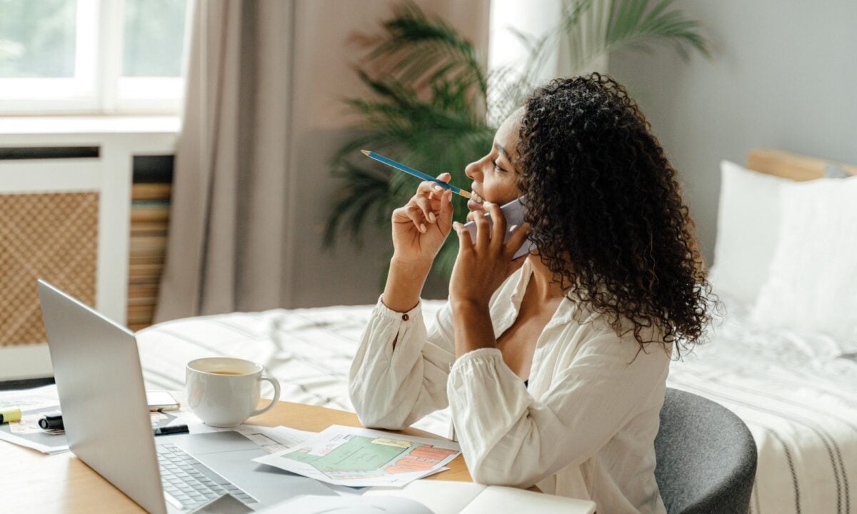 real estate agent on the phone sits at a desk trying to decide between luxury presence vs lofty as a website provider