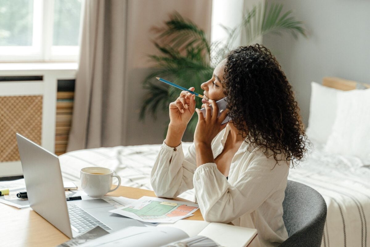 real estate agent on the phone sits at a desk trying to decide between luxury presence vs lofty as a website provider
