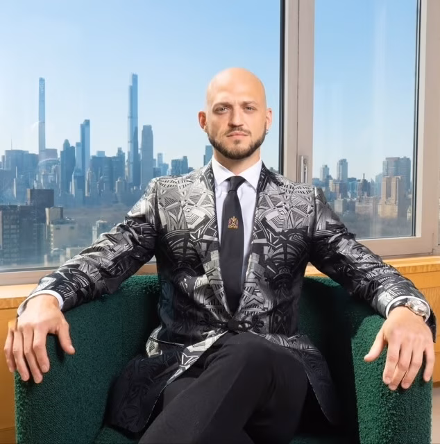 real estate agent nile lundgren seated in front of a window showing the NYC skyline