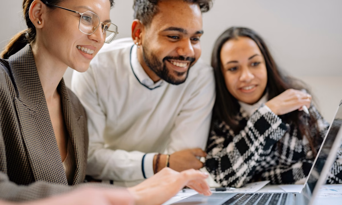Two consumers crowd around a laptop screen as their realtor shows them listings on their IDX-enabled real estate website