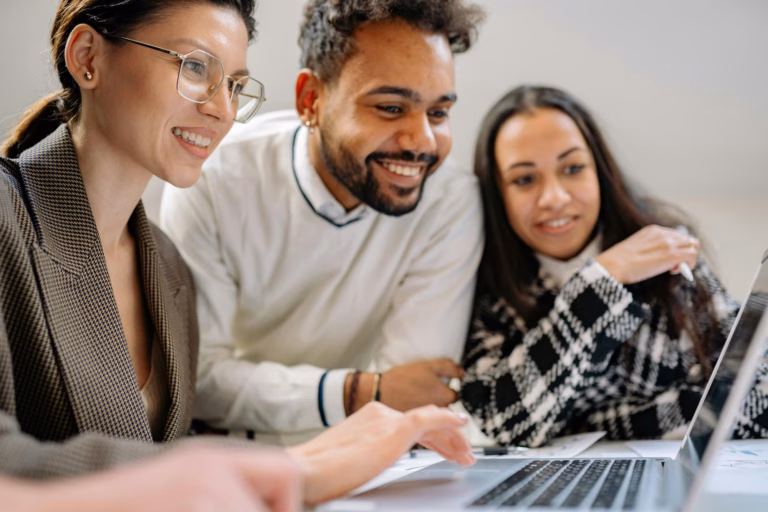 Two consumers crowd around a laptop screen as their realtor shows them listings on their IDX-enabled real estate website