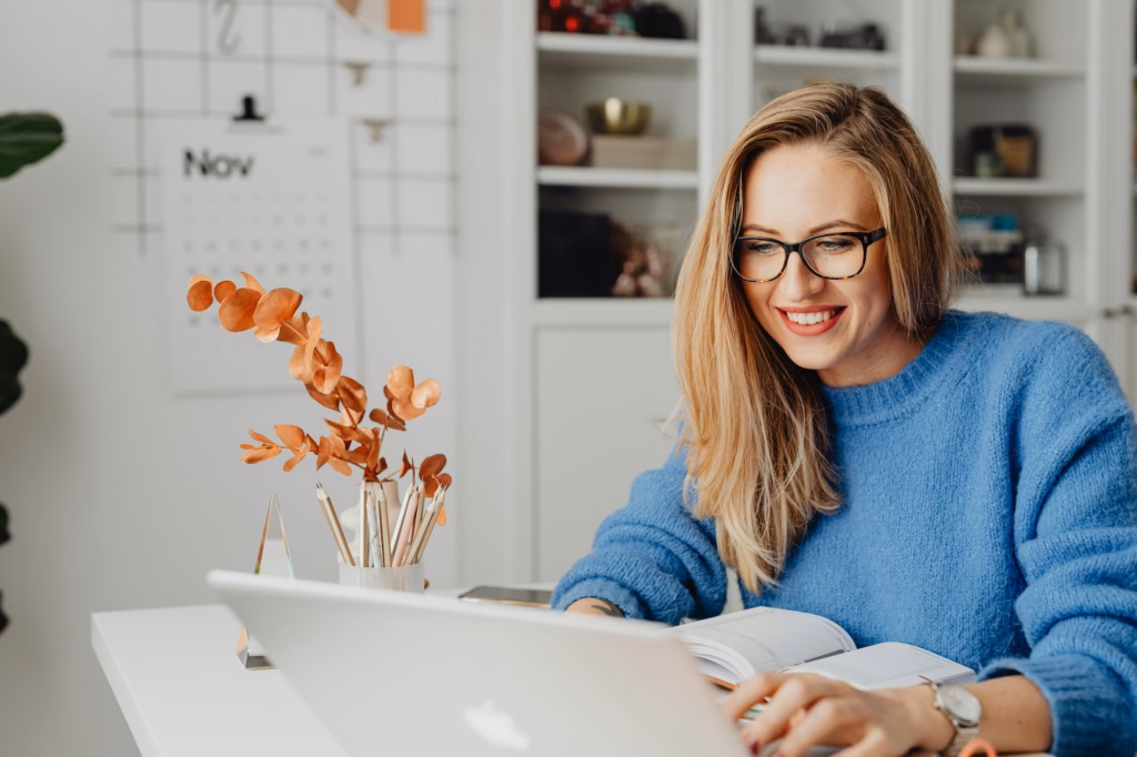 A real estate agent smiling at her laptop because her Luxury Presence website generated a new lead for her business