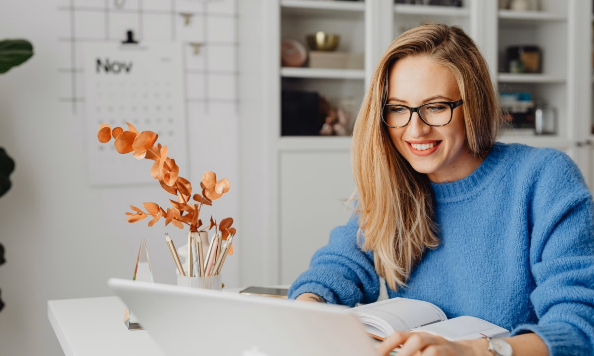A real estate agent smiling at her laptop because her Luxury Presence website generated a new lead for her business