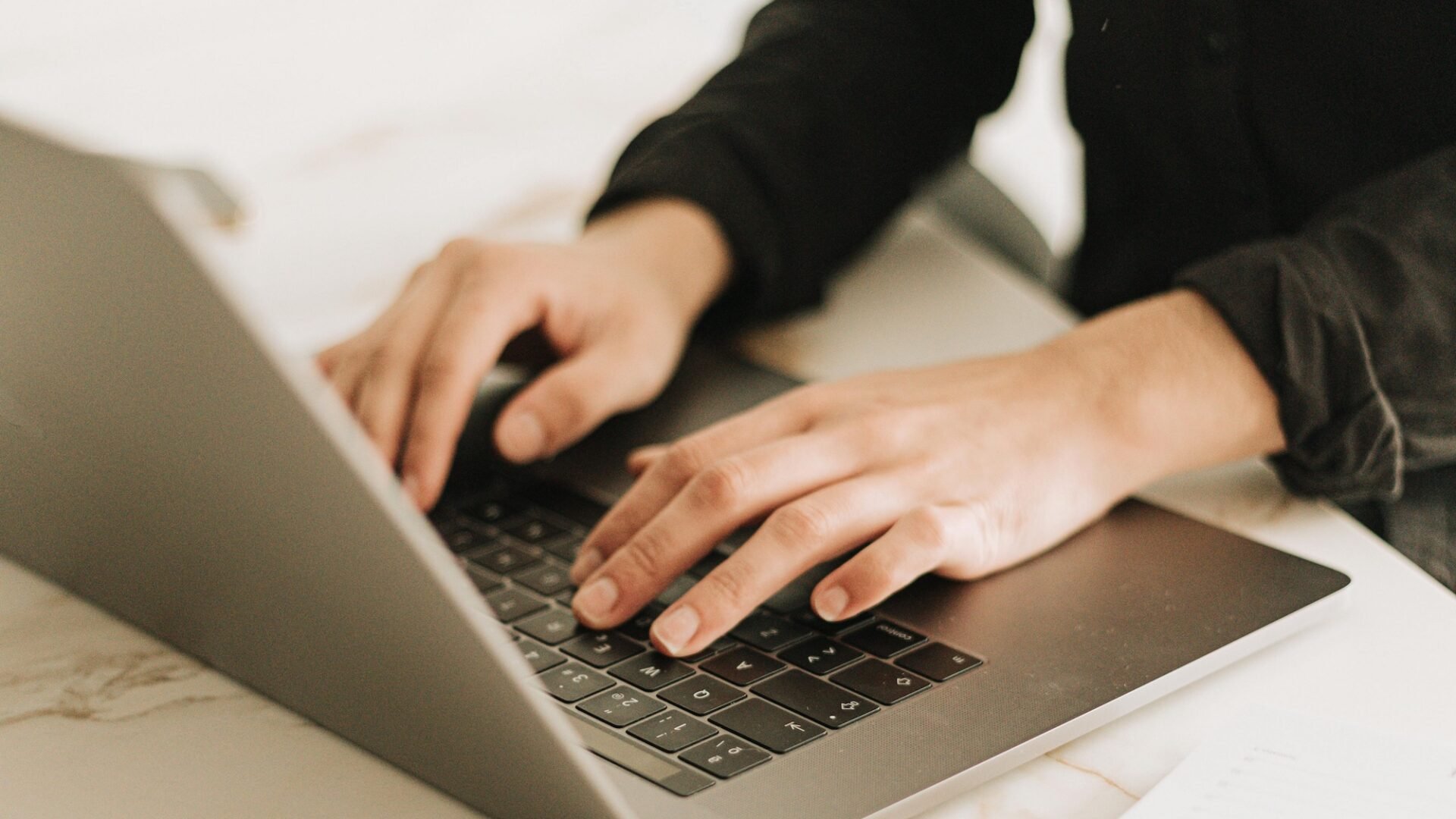 real estate agent sits at a laptop on a white desk trying to choose between the Real Estate Website Builders