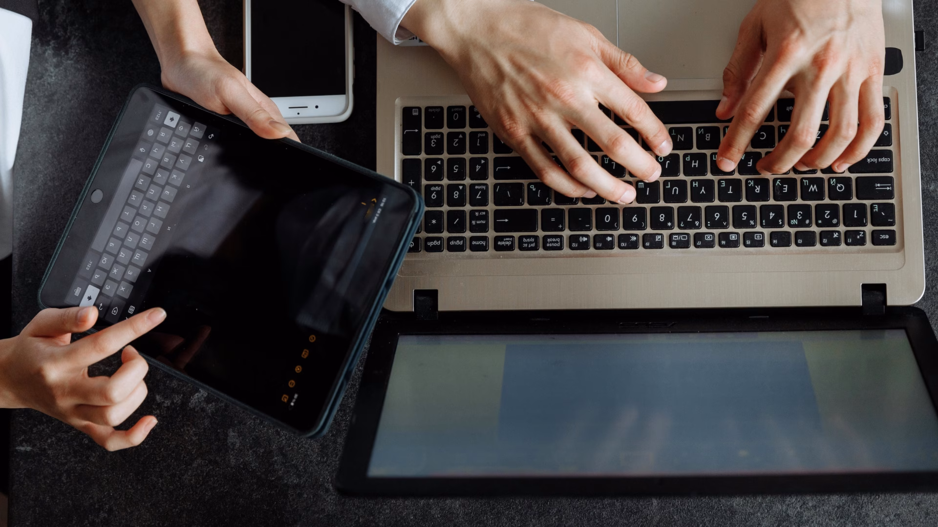 Two real estate agents sit in front of a tablet and laptop debating the differences between Luxury presence vs. Agent Image