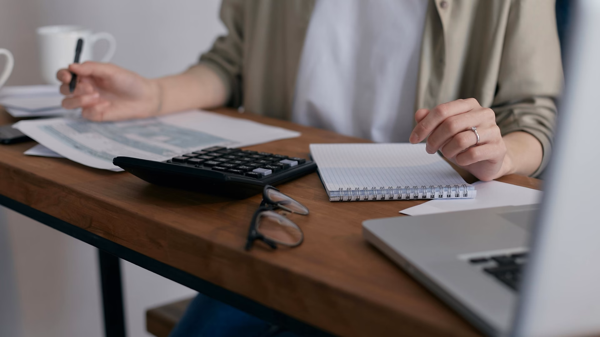 Real estate agent sits at desk in front of laptop using calculator to determine the right choice between Luxury Presence vs. BoldTrail
