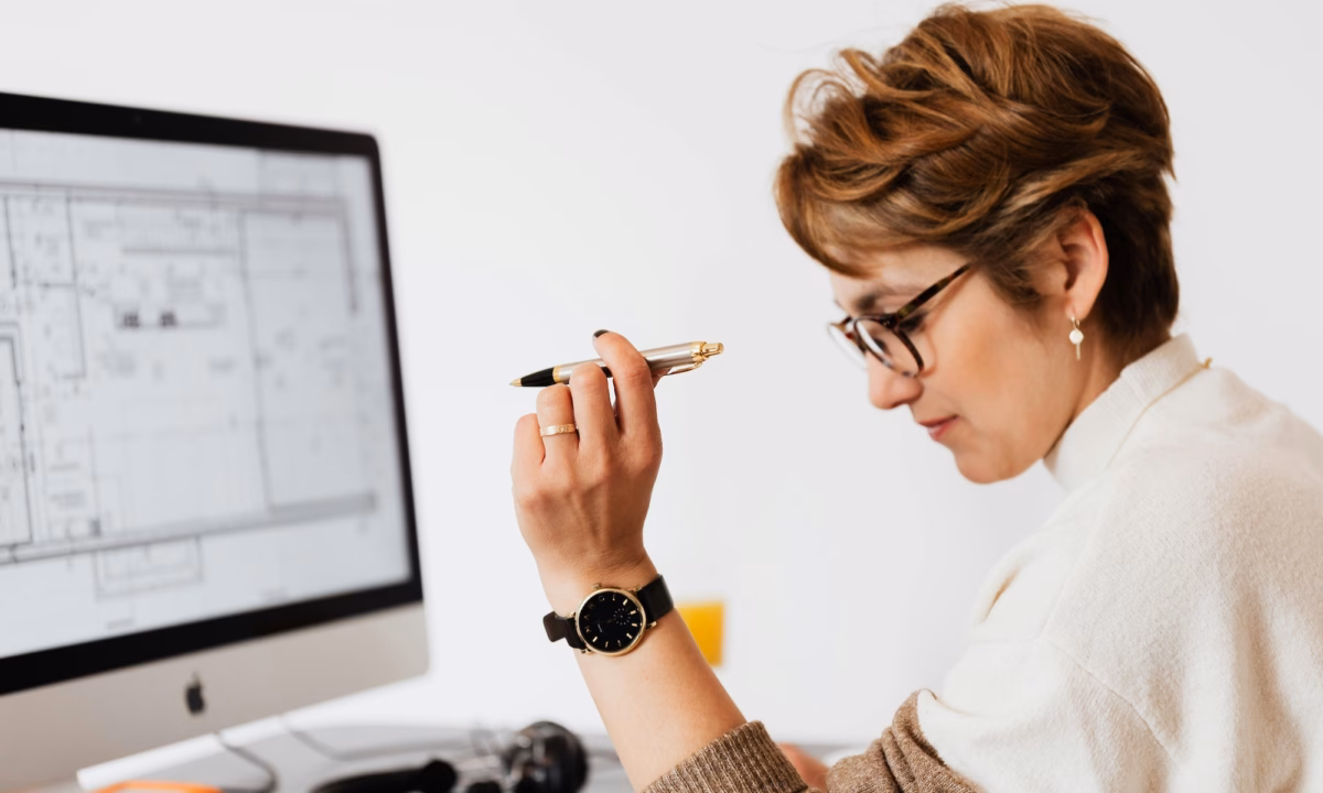 A real estate broker sits in front of a desktop with a floorplan on it, considering the choice between luxury presence vs. agent image