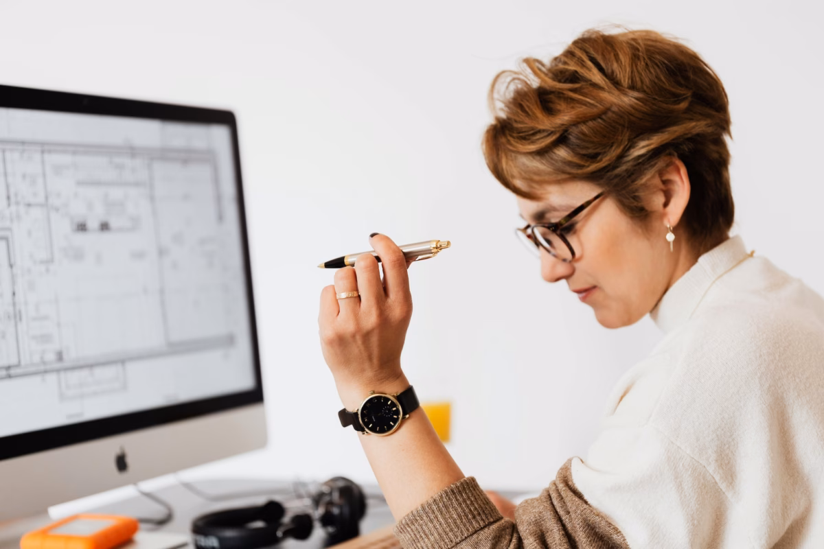 A real estate broker sits in front of a desktop with a floorplan on it, considering the choice between luxury presence vs. agent image